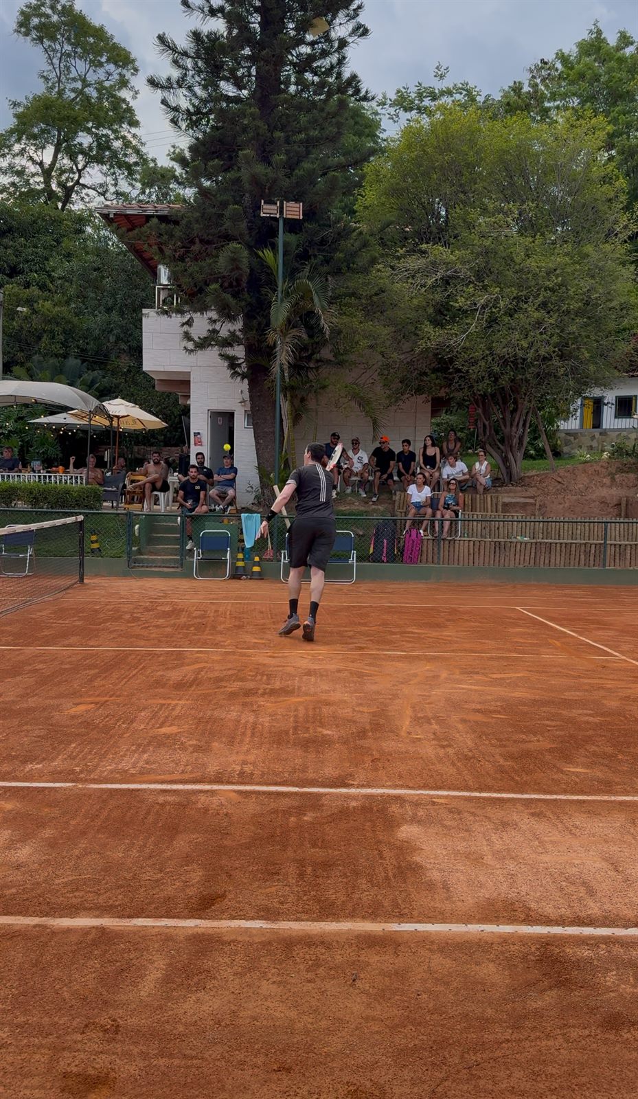 Partida na quadra de saibro da DG Tennis Sports com torcida acompanhando